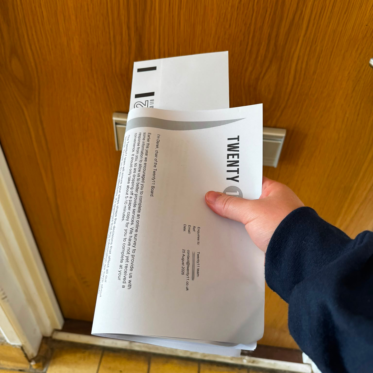 A member of the Twenty11 team posting a survey form through a tenant's door